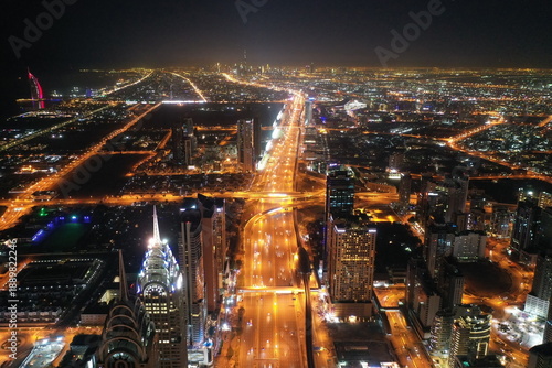Aerial night view of Dubai skyline. Illuminated Sheikh Zayed Road highway traffic and modern skyscrapers in United Arab Emirates city center.