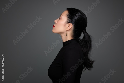 An elegant woman in her twenties, with her black hair tied up, wearing an elegant black dress, wearing red lipstick, exuding timeless charm and graceful elegance.