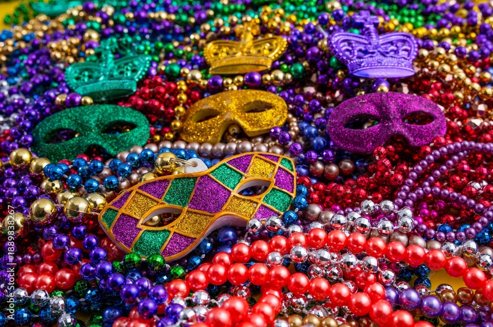 Fototapeta premium Mardi Gras beads in glittering yellow, green, purple, and gold. Sparkling festive background for Mardi Gras in traditional colors.