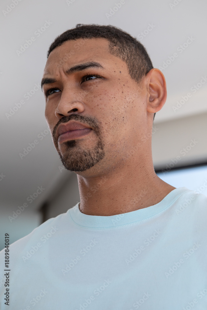 Fototapeta premium Middle aged man gazing thoughtfully upward toward left while sitting at home with TV screen