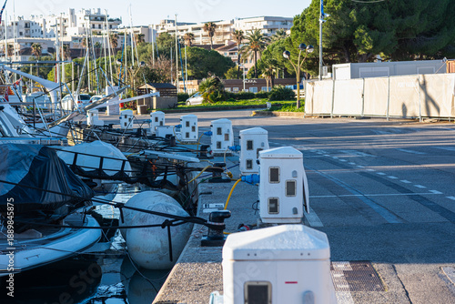 Marina dockside view with multiple white utility pedestals providing power and water hookups for luxury yachts.