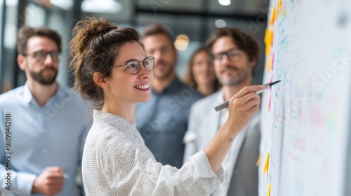 Professional Project Manager Leads a Team Discussion in a Modern Office Setting While Pointing at Notes on a Large Board