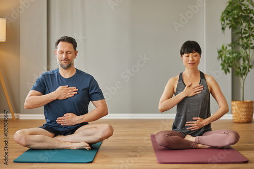 Man and woman practicing yoga and meditation at home for wellbeing