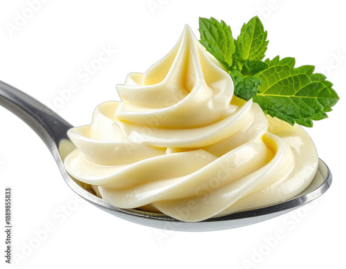 Close-up of whipped cream on a spoon with mint leaves against a black backdrop