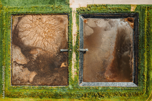 Top-down drone view of farm waste lagoons and storage basins. Agricultural byproduct management, rural industry, and environmental impact of modern farming operations.