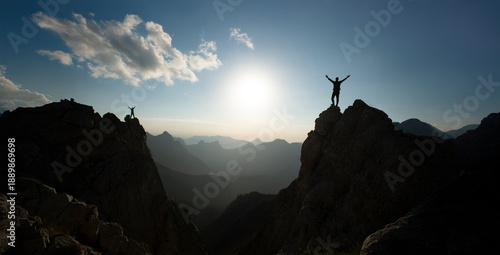 At the summit, two climbers successfully complete a climb at sunrise.