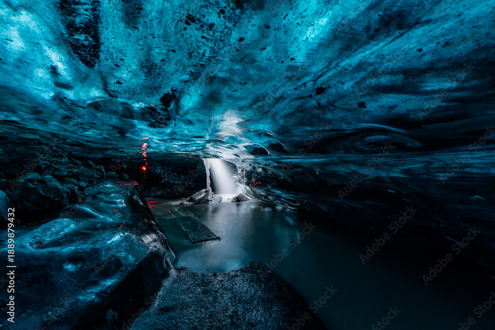 Fototapeta premium Spectacular glacial ice cave in Iceland. Surreal deep blue tunnel forming a unique natural attraction for winter adventure travel.
