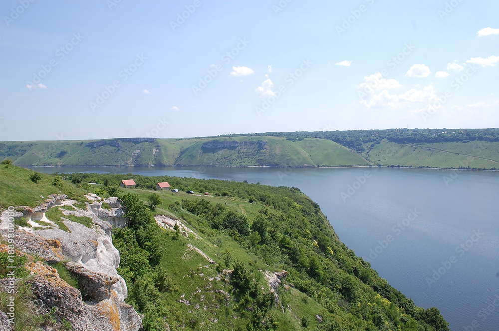 Obraz premium Scenic river valley with lush greenery and clear blue sky