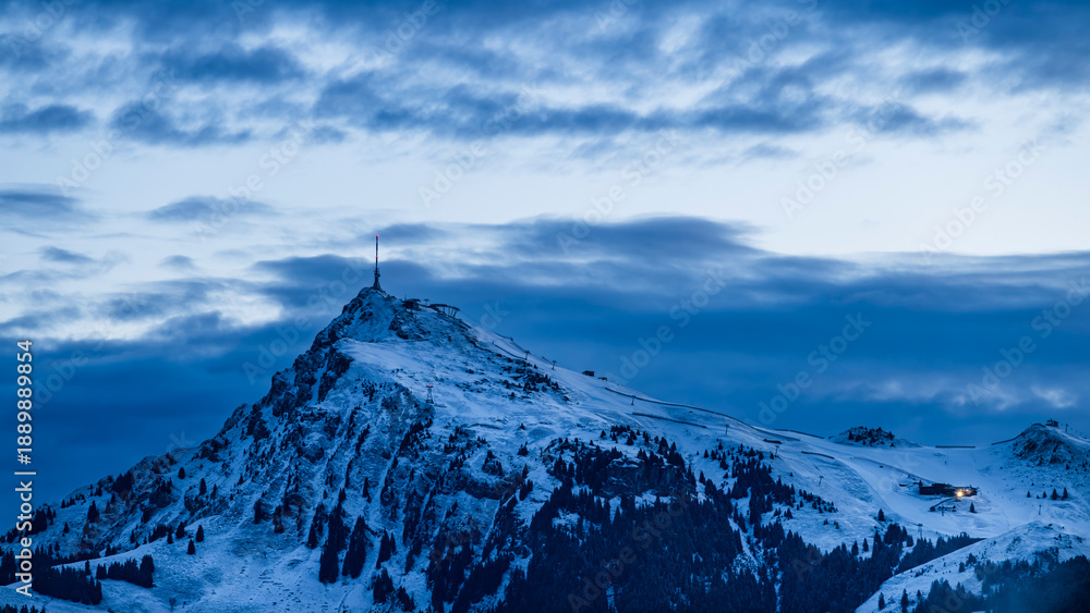 Naklejka premium Snow Covered Alpine Peak at Blue Hour with Dramatic Clouds