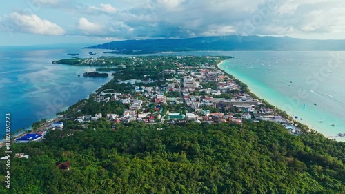 Drone moves slowly above Boracay coastline revealing turquoise sea and town