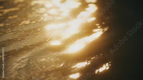 Golden water surface reflects bright sunlight, creating shimmering patterns and an abstract texture, representing concepts of peace, warmth, and natural beauty