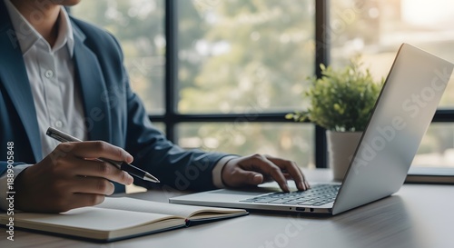 Businessman working on laptop and writing notes in office