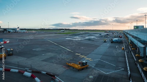 Airplanes taxi on the runway of a bustling international airport under hazy conditions. Multiple aircraft are visible, showcasing a busy airport environment with modern terminals.