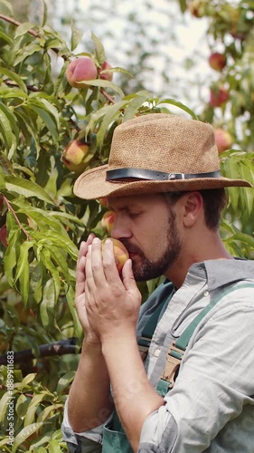A man picks and enjoys a peach while standing among garden plants during the day.