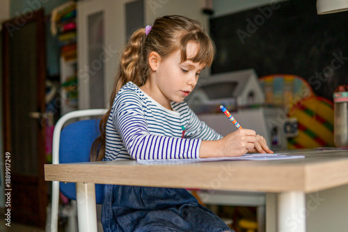 Nine year old schoolgirl doing homework at desk in her room, elementary education concept
