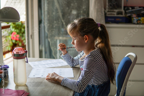 Φωτογραφία Nine year old schoolgirl doing homework at desk in her room, elementary educatio