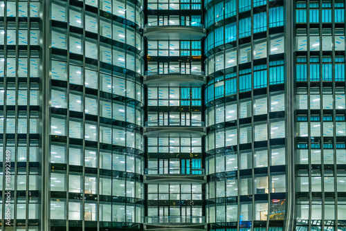 Canvas Print Modern glass office building facade at night with illuminated windows and repeating geometric pattern in Hong Kong city, China
