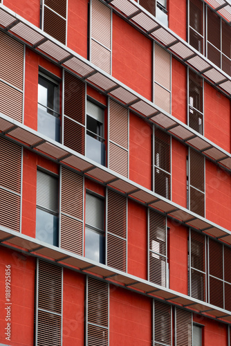 Modern Red Building Facade Featuring Contemporary Metal Sunshades and Geometric Window Design in Urban Architectural Style