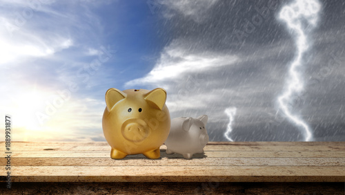 Tableau sur toile Two piggy banks on a wooden table against a split sky of sunshine and storm, sym