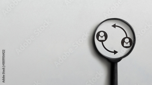 A magnifying glass focuses on icons of two people with circular arrows, symbolizing teamwork, communication, feedback, and professional exchange on a clean grey background with copy space