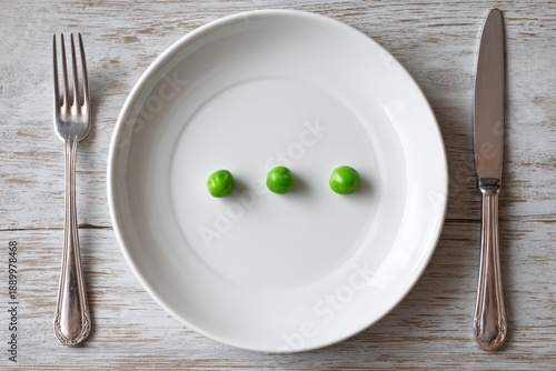 Minimal still life of three peas on a plate with cutlery illustrating scarce nutrition