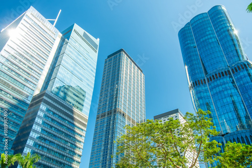 Photography Modern skyscrapers with glass facades against blue sky and green trees in Hong Kong city, China