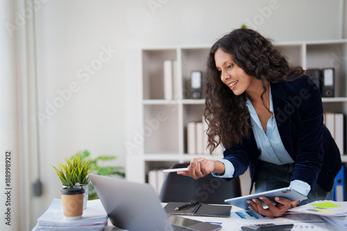 Bild auf Leinwand Young professional woman happily managing business tasks, looking at a laptop wh