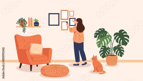 Young woman decorating her home by hanging various picture frames on the wall with her ginger cat watching in a bright living room.