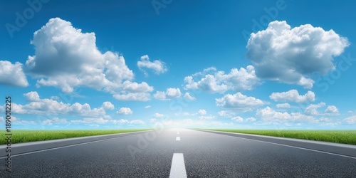 A serene road stretches toward the horizon under a bright blue sky adorned with fluffy clouds and green grass on either side.