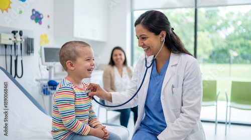 Smiling female pediatrician examining a happy young boy with a stethoscope. Child patient recovery check-up in a modern clinic
