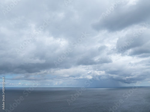 Dramatic aerial view over Turisalu (Estonian - Türisalu) coast with dark storm clouds sweeping across calm, steel-blue Baltic Sea waters. Dynamic weather, soft horizon light, and vast open seascape.