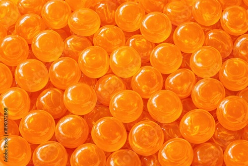 Close-up view of numerous glossy orange marbles arranged closely together, showcasing their smooth surfaces and vibrant color in a detailed composition