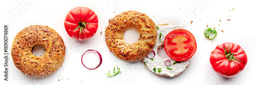 Vegetarian bagels panorama, bread with tomato and onion, overhead flat lay shot on a white background, with fresh salad leaves