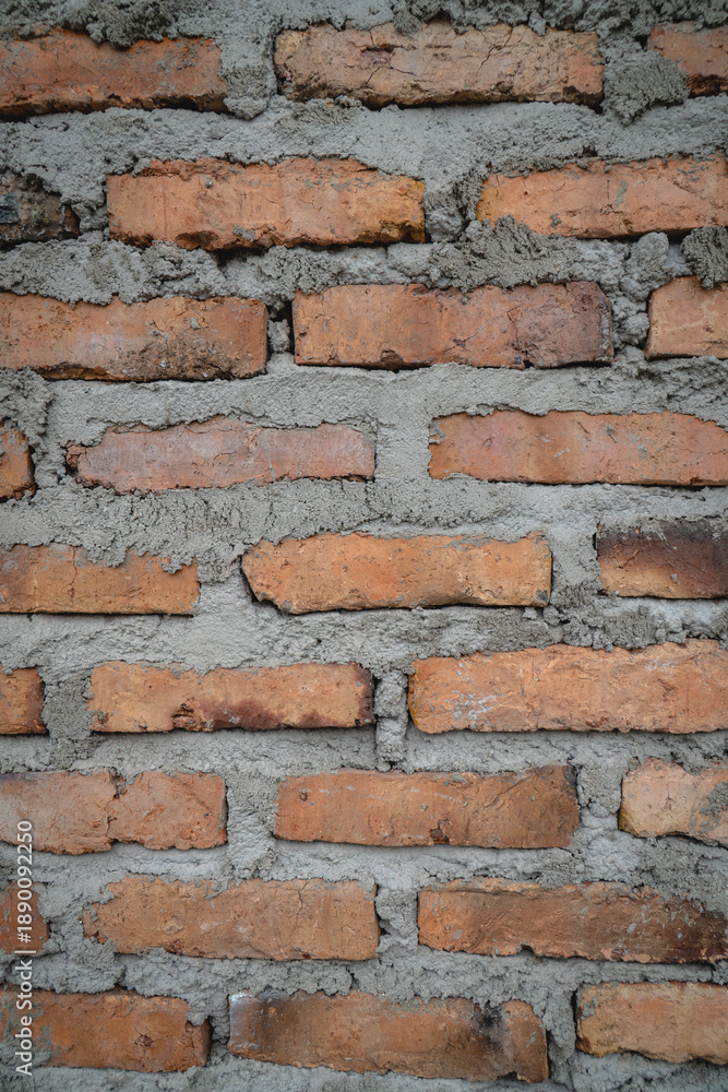 Obraz premium Close-up of weathered brick wall texture with visible mortar lines, showing rustic construction details and natural color variations.