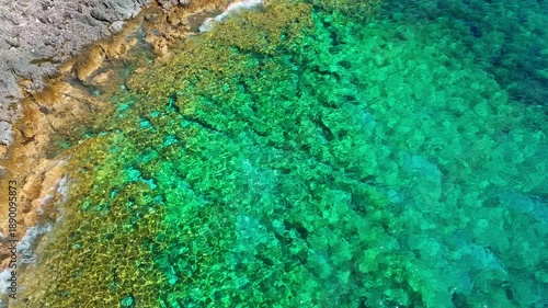 Aerial drone view of crystal clear waters and rocky shoreline at ...