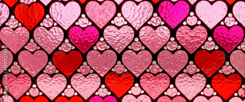 Stained glass mosaic window made from pink and red heart shaped details as a background. Valentine’s Day, love, wedding concept banner for design.