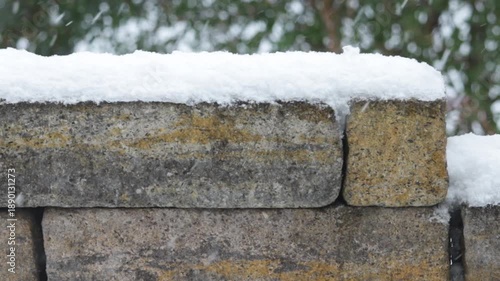 snow-covered stone wall in silent snowfall