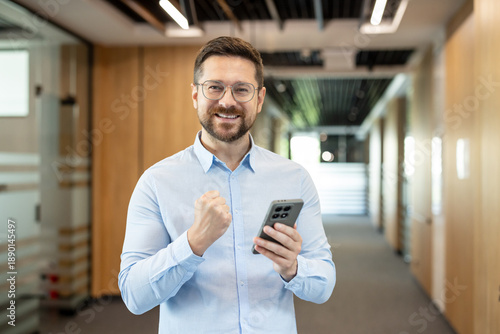 Εκτύπωση καμβά Optimistic man celebrating business achievement or online victory, holding a mob
