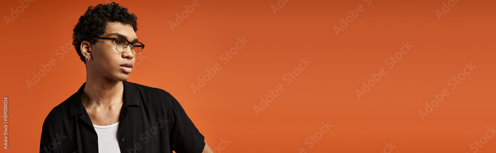 Obraz premium Stylish young man with eyeglasses poses in vibrant studio setting