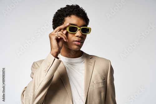 Stylish young African American man showcases trendy sunglasses in studio setting