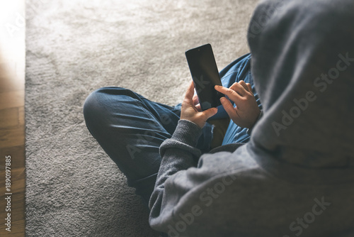 Bilde på lerret A Young Person Engaged with Their Smartphone While Sitting on the Floor in a Coz