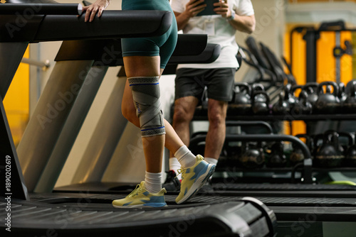 Billede på lærred Caucasian young adult woman walking on treadmill with knee brace during physical