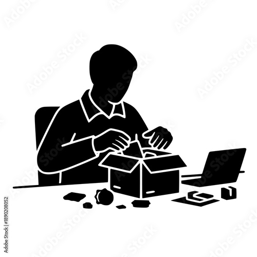 Silhouette of a person carefully unpacking contents from a cardboard delivery box while working at a desk with a laptop.