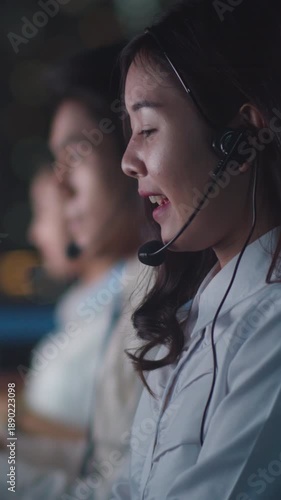 Vertical Screen : Asia young call center team or customer support service executive use computer and microphone headset working technical support in late night office. Telemarketing or sales job.
