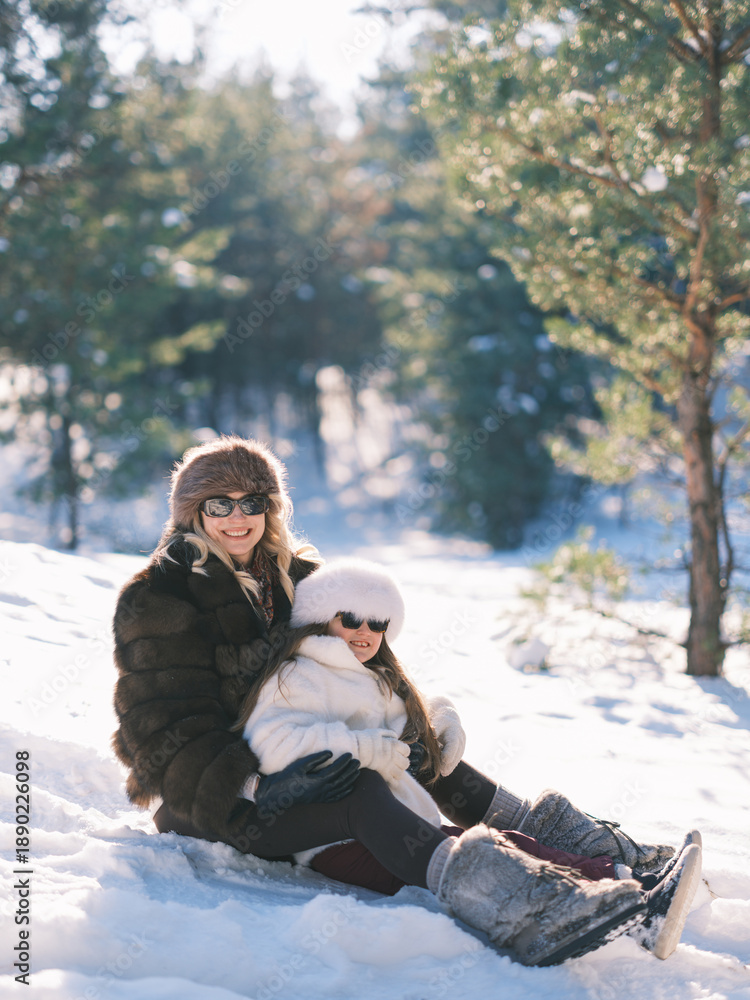 Obraz premium Mother and daughter have fun sitting on snow. Slavic style winter fashion.