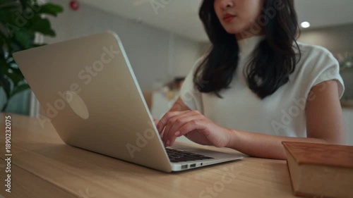 Young female university student studying and typing on her laptop computer. Modern learning technology and online education concept