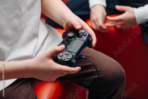 Foto black gamepad in hands, young boy playing game console, selective focus