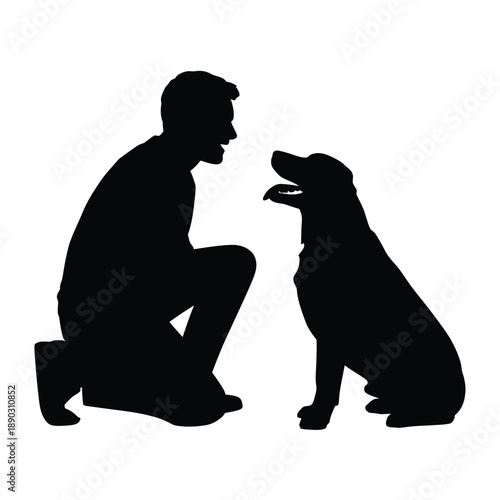 Silhouette of a man crouching and facing a seated labrador retriever