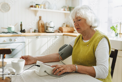 Photos Side view of senior lady measuring blood pressure at home feeling unwell as weat