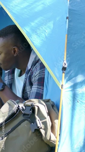Vertical video: Lifting sandwich plaid dad and yellow son eating in blue tent with pack bottle
